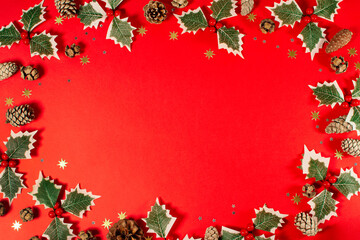 A red background with a row of green holly leaves and gold stars. Christmas greeting.