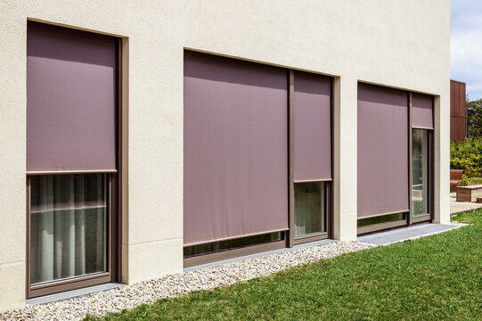 Window Blinds Shades Outdoor. External Roller Blinds on Large Panoramic Windows Door Outside. Modern Fabric Shutters of Facade Building. 