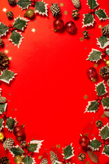 A red background with a row of green holly leaves, red and gold balls. Christmas greeting.