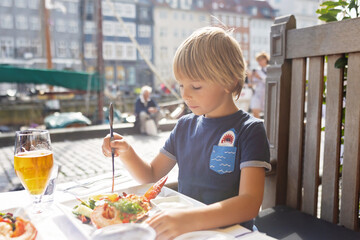 Family with children, having lunch in a restaurant in Coppenhagen, eating local fish and lobster thermidor with salad and fries