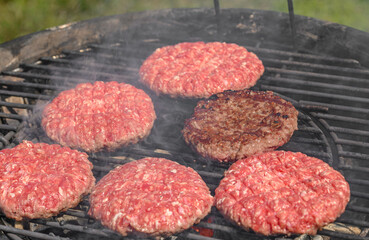 Burgery wołowe, wołowina na ruszcie grilla, dym unosi się z paleniska