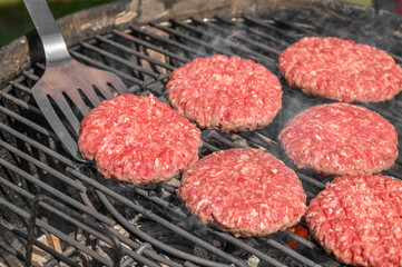 Grillmaster szykujący piękne soczyste burgery do smażenia na ruszcie 