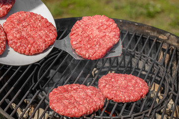 Piękne apetyczne burgery z mielonego mięsa wołowego na rozgrzanym ruszcie na grillu, 