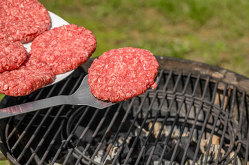 Szef kuchni wykłada burgery z surowego mięsa wieprzowego na rozgrzany ruszt na grillu, smażenie bez tłuszczowe, zdrowy fast food 