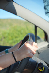 A person is driving a car with a black wrist band