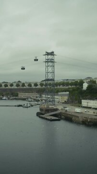 Le t&eacute;l&eacute;ph&eacute;rique de Brest traversant un port historique sous un ciel couvert. Plan vertical, 9:16.