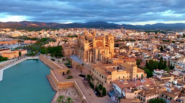 flying towards cathedral of Palma de Mallorca at sunrise, aerial Palma de Mallorca cityscape. Cathedral of Santa Maria, Royal Palace of La Almudaina. Balearic Islands. Spain