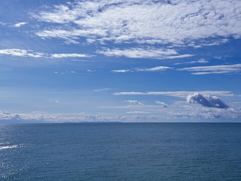 Sky clouds above blue ocean calm water. 