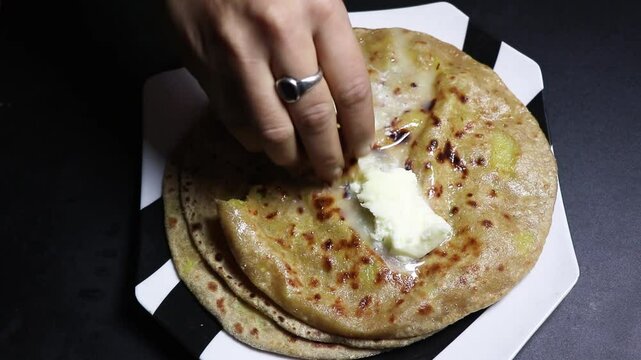 Aloo Paratha made with whole wheat flour, boiled potatoes, and spices  served with white Butter.