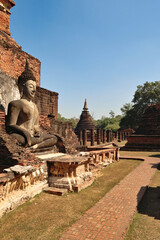 Big buddha statue next to the foot path at the Wat Mahathat Temple with a chedi, stupa and pillars...