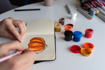 Finalizing a pumpkin painting with gouache in a sketchbook