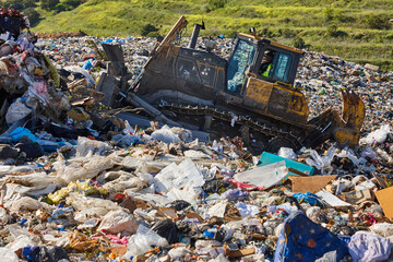 Heavy machinery shredding garbage in an open air landfill. Pollution