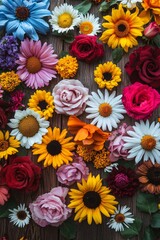 A top down view of a collection of vivid flowers like sunflowers, daisies, and roses, arranged symmetrically on a wooden table. 