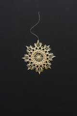 Snowflakes are made of straw on a black background. Straw star. Christmas decor. Top view. Straw weaving. Lutsk, Ukraine