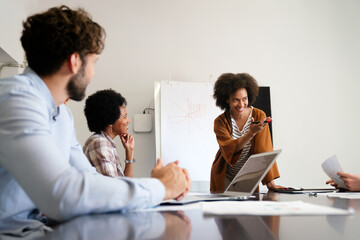 Fototapeta premium Smiling diverse colleagues gather in boardroom brainstorm discuss financial statistics together