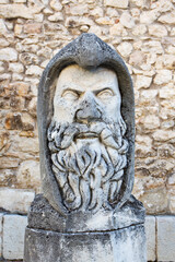 Ancient stone sculpture of a medieval warrior bust, emphasizing armor and heroic features in timeless style
