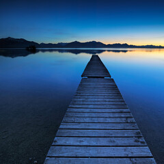 Fototapeta premium Wooden Pier by Lake Chiemsee at Sunset against the Bavarian Alps, Bavaria, Germany