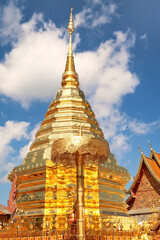 Naklejka premium The golden central stupa, pagoda and a golden umbrella, parasol at the Wat Phra That Doi Suthep Temple, in front of a blue sky with clouds, Chiang Mai, Thailand