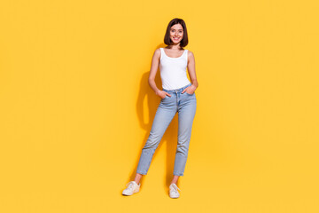 Full body photo of attractive young girl hands pockets posing wear trendy white outfit isolated on yellow color background