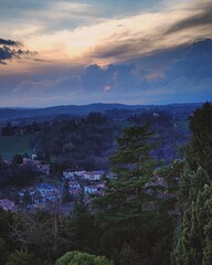Aerial view of Conegliano, Italy, from the top of Castello di Conegliano, captured in blue hour with intentional dark tones to highlight the dramatic evening sky and landscape of the village below.