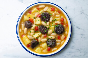 Bean stew with black pudding, peppers and potatoes. Top view table with decoration.