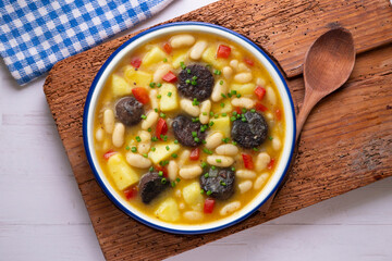 Bean stew with black pudding, peppers and potatoes. Top view table with decoration.