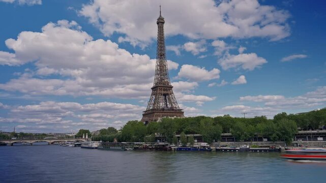 Timelapse of the Eiffel Tower along the river Seine with flyboats passing by with motion blur. Sunny but cloudy spring summer day paris city famous riverside bay tower view bridge time lapse panorama