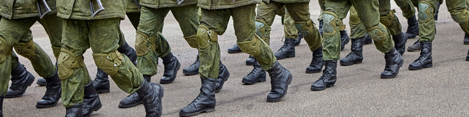 Soldiers marching in formation during a military parade on a clear day in an urban setting
