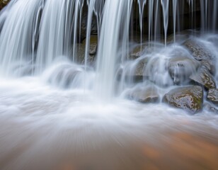Obraz premium Serene waterfall cascading over smooth stones in a tranquil setting.
