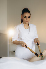 Massage of human foot in spa salon with bamboo sticks. Closeup of feet,