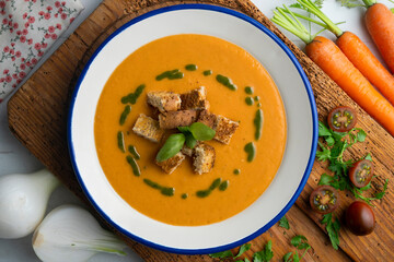 Tomato soup with basil oil and croutons. Top view table with  decoration.