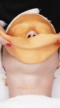 Close-up of a cosmetologist removing an alginate mask in a contemporary skincare center. This scene highlights the meticulous process and expertise involved in advanced facial treatments.