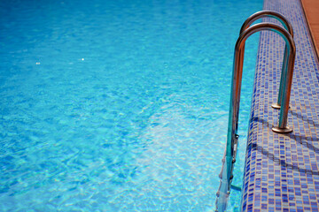 ladder for descending into the pool. ripples on the blue water in the pool. water purification in...