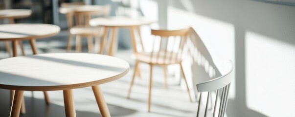 Minimalist wooden furniture in a bright space, featuring tables and chairs bathed in natural light.