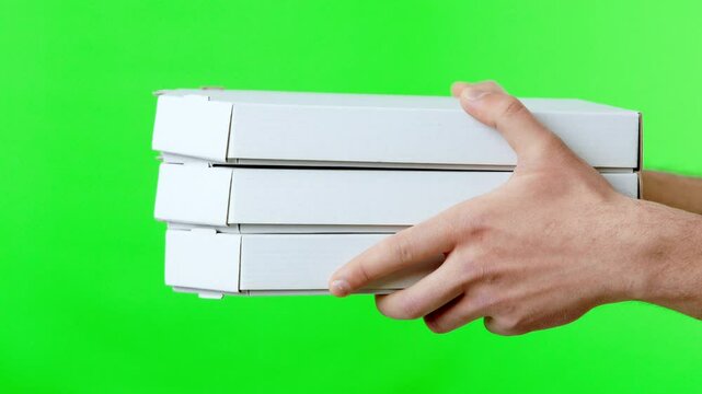 A hand carries three stacked pizza boxes, showcasing a casual dining theme with a vibrant green backdrop, ideal for promotional purposes or food-related content.