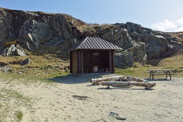 An open shelter and fireplace at seashore in sunny spring weather, Grense Jakobselv, Norway.