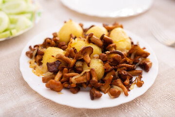 Delicious forest mushrooms chanterelles with young potatoes fried on white plate