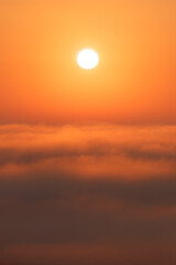 Warm dawn above the clouds. The moment of sunrise, which rises above the clouds, immersing everything in gentle orange and yellow tones. The sun slowly rises, lighting up the sky