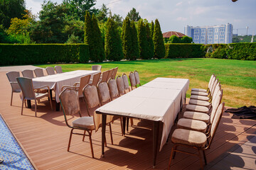 Empty banquet tables and chairs on the lawn in the park. Banquet in nature in summer.