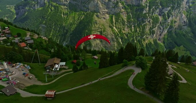 Aerial view beautiful of Paraglider flying with a picture of the Swiss flag on it in the alpine mountains in Switzerland