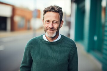 Naklejka premium Portrait of a smiling man in his 40s dressed in a warm wool sweater on pastel teal background