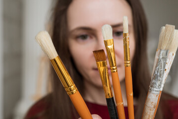 Painter choosing paintbrush holding few of them in hand