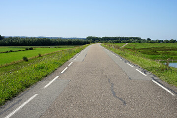 Road for cars and bicyclists on top af a river dike in the floodplains near the river Waal and the village Erlecom, Netherlands