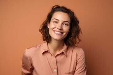 Obraz premium Portrait of a smiling woman in her 30s donning a classy polo shirt on pastel brown background