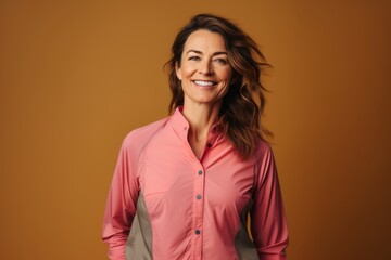 Fototapeta premium Portrait of a smiling woman in her 40s sporting a breathable hiking shirt isolated in pastel brown background