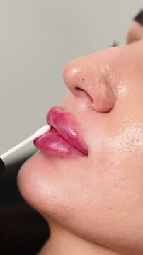 Vertical video. Close-up of a cosmetologist applying a hydrating gel to a client's lips after an injection. This scene emphasizes the post-procedure care and hydration, ensuring optimal results 