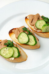 Savory canapes topped with creamy spread and cucumber slices served on toasted bread at a casual gathering
