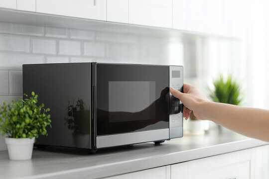 Hand setting a microwave on a modern kitchen counter, showcasing convenient and easy meal preparation in a contemporary home