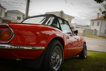 Fototapeta premium Exterior of old red retro car on green lawn at home. Concept of love for retro style, vintage stuff, car enthusiasts, rich life.