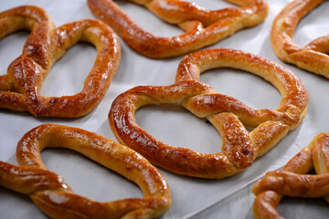 Freshly baked, golden-brown pretzels laid out on parchment paper, glistening with a slight sheen of butter. These crispy yet soft pretzels are perfect for snacking